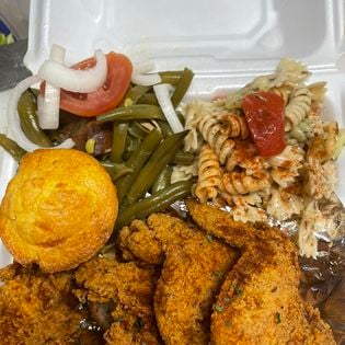 Soul food plate with fried fish, cornbread muffin, green beans and pasta salad